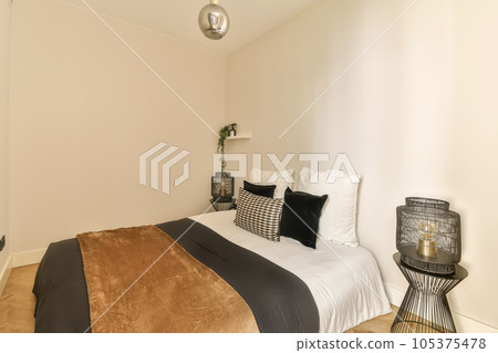 a bedroom with white walls and wood flooring the room is decorated in neutral tones, including black and gold accents 105375478