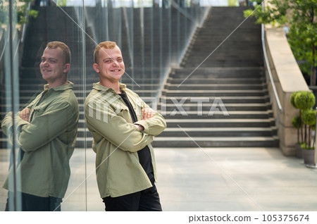 A pensive man stands against the backdrop of a skyscraper. 105375674