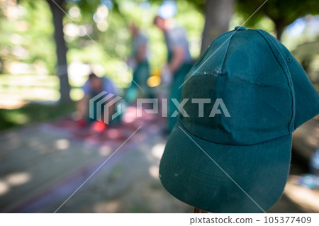 A construction worker's green baseball cap hangs on a wooden peg. A construction worker's green baseball cap hangs on a wooden peg. 105377409