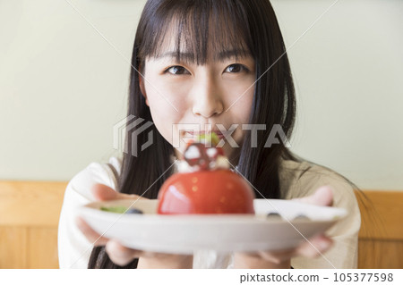 A young female college student showing a cute cake at a cafe 105377598