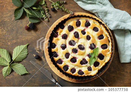 Sweet pie with blackberry and custard on wooden table. Homemade blackberry pie. Vegan gluten-free pastry, vegan desserts. View from above. Sweet pie with blackberry and custard on wooden table. Homemade blackberry pie. Vegan gluten-free pastry, vegan desserts. View from above. 105377738