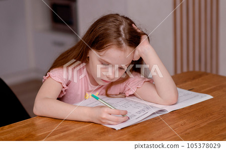 The girl sits at the table and solves problems, does her homework. School theme, vacation assignments. High quality photo The girl sits at the table and solves problems, does her homework. School theme, vacation assignments. High quality photo 105378029