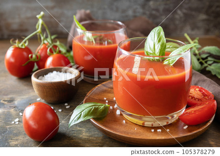 Glasses of fresh tomato juice with tomatoes, salt on wooden table. Vegetable tomato drink for a healthy diet. Glasses of fresh tomato juice with tomatoes, salt on wooden table. Vegetable tomato drink for a healthy diet. 105378279