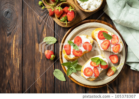 Sandwich with strawberries and soft cheese on wooden background. Berries toast breakfast, healthy food. View from above. 105378307