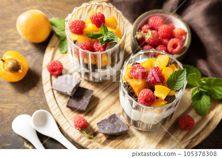 Triffle of chocolate biscuit with yogurt and fresh berries and fruits. Two portioned glass parfafait dessert. Summer healthy diet breakfast, snack concept. 105378308