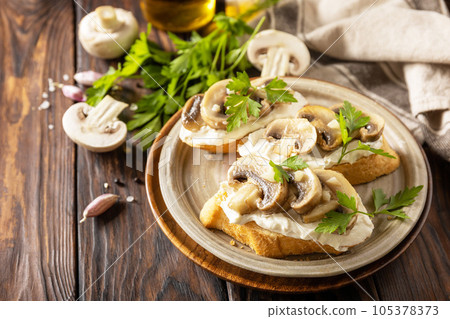 Toasted sandwich from baguettes bread with soft cheese and grilled mushrooms on wooden rustic  table. Homemade bruschetta with mushrooms. Copy space. 105378373