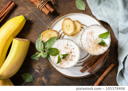 Banana smoothie with cinnamon in drinking glass on a wooden background. Detox menu. View from above. 105378406
