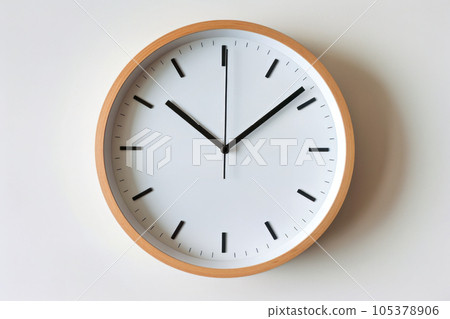 A simple clock hanging on a white wall 105378906