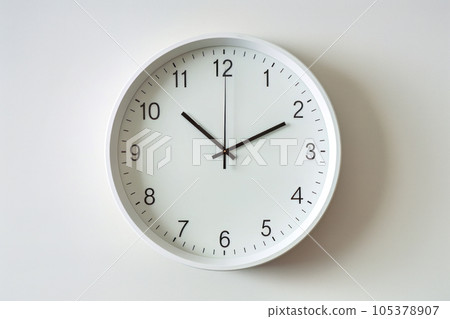 A simple clock hanging on a white wall 105378907