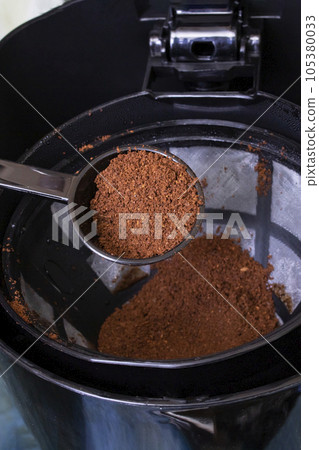 Spoon pours coffee into container of coffee maker 105380033