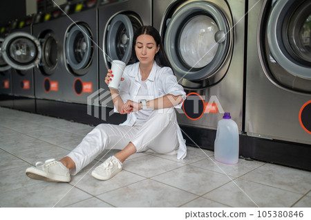 Woman waiting in public laundry room. Woman waiting in public laundry room. 105380846