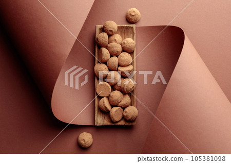 Tasty chocolate truffles in a wooden dish on a brown background. Tasty chocolate truffles in a wooden dish on a brown background. 105381098