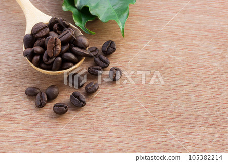 Close up coffee beans in wood spoon and fresh green leaf 105382214
