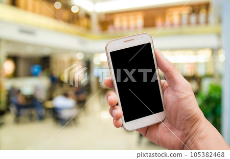 Hand holding smart phone with blurred background 105382468