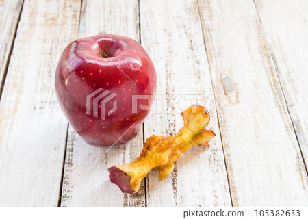 Red apple and apple core on a white wooden background 105382653
