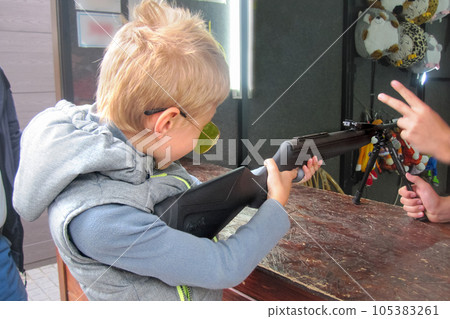boy learns to shoot at shooting range under guidance of an instructor 105383261