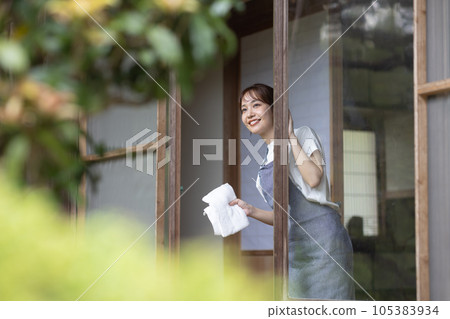 一位年輕女子正在擦一棟古老民居的窗戶 105383934