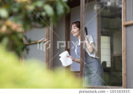 一位年輕女子正在擦一棟古老民居的窗戶 105383935
