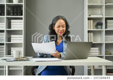 Middle age businesswoman looking at laptop screen, analyzing financial data, stock market information at workstation 105384645