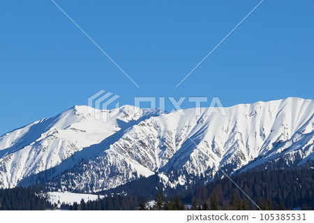 Mountain with snow. Alps. Switzerland. Panoramic view of the Snowy Alps and blue sky around the Titlis mountain. French Alps. Alpine mountains. Descent peaks on the Austrian snow slopes. ski slopes. Mountain with snow. Alps. Switzerland. Panoramic view of the Snowy Alps and blue sky around the Titlis mountain. French Alps. Alpine mountains. Descent peaks on the Austrian snow slopes. ski slopes. 105385531
