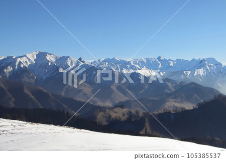 Mountain with snow. Alps. Switzerland. Panoramic view of the Snowy Alps and blue sky around the Titlis mountain. French Alps. Alpine mountains. Descent peaks on the Austrian snow slopes. ski slopes. Mountain with snow. Alps. Switzerland. Panoramic view of the Snowy Alps and blue sky around the Titlis mountain. French Alps. Alpine mountains. Descent peaks on the Austrian snow slopes. ski slopes. 105385537