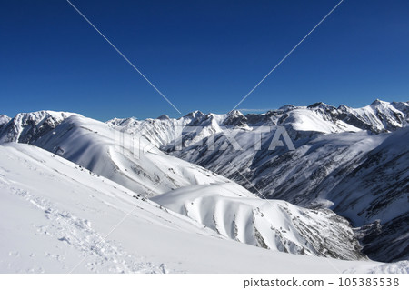 Mountain with snow. Alps. Switzerland. Panoramic view of the Snowy Alps and blue sky around the Titlis mountain. French Alps. Alpine mountains. Descent peaks on the Austrian snow slopes. ski slopes. Mountain with snow. Alps. Switzerland. Panoramic view of the Snowy Alps and blue sky around the Titlis mountain. French Alps. Alpine mountains. Descent peaks on the Austrian snow slopes. ski slopes. 105385538