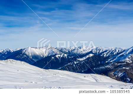 Mountain with snow. Alps. Switzerland. Panoramic view of the Snowy Alps and blue sky around the Titlis mountain. French Alps. Alpine mountains. Descent peaks on the Austrian snow slopes. ski slopes. Mountain with snow. Alps. Switzerland. Panoramic view of the Snowy Alps and blue sky around the Titlis mountain. French Alps. Alpine mountains. Descent peaks on the Austrian snow slopes. ski slopes. 105385545