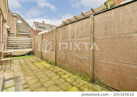 an outside area with a brick wall and green grass in the yard is surrounded by small houses on either sides an outside area with a brick wall and green grass in the yard is surrounded by small houses on either sides 105385610