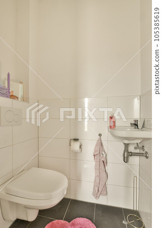 a white bathroom with pink towels on the floor and a toilet in the corner next to the sink is visible a white bathroom with pink towels on the floor and a toilet in the corner next to the sink is visible 105385619