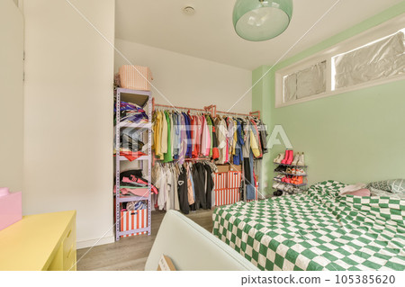 a green and white checkereded bed in a room with two closets on either sides, one is open to the other a green and white checkereded bed in a room with two closets on either sides, one is open to the other 105385620