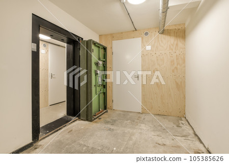 an unfinished room with wood paneling on the walls, and a green door in the wall is being installed an unfinished room with wood paneling on the walls, and a green door in the wall is being installed 105385626