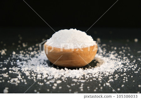 salt into a wooden spoon from a bowl on a black salt into a wooden spoon from a bowl on a black 105386033
