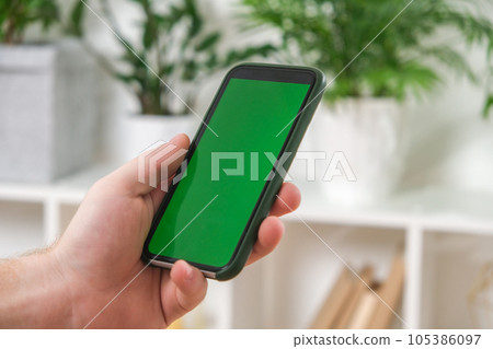A man holds a phone with a green screen in his A man holds a phone with a green screen in his 105386097