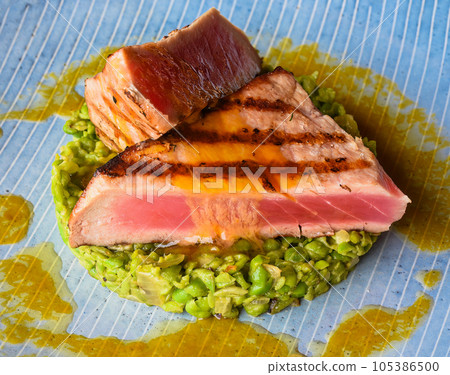 Tuna steak medium rare served with peas isolated on black background side view Tuna steak medium rare served with peas isolated on black background side view 105386500