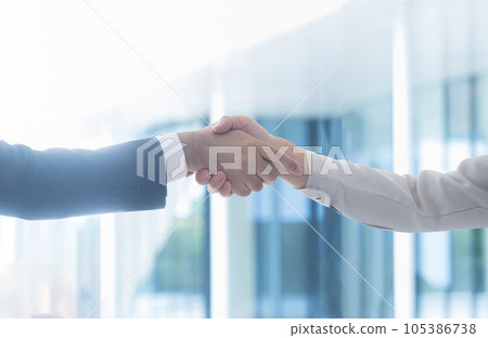 A man in a suit and a man in work clothes shaking hands in business contract scenes, etc. 105386738