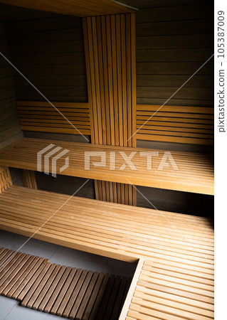 Interior of Finnish sauna, classic wooden sauna with hot steam. Wooden interior baths, wooden benches, sauna, spa complex. 105387009