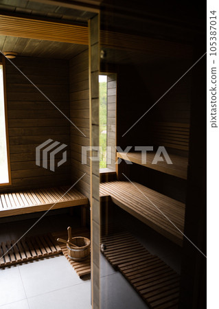 Interior of Finnish sauna, classic wooden sauna with hot steam. Large standard design classic wooden sauna interior. Interior of Finnish sauna, classic wooden sauna with hot steam. Large standard design classic wooden sauna interior. 105387014