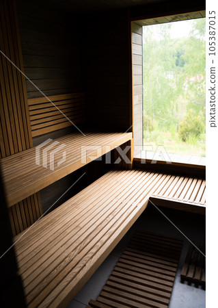 Interior of Finnish sauna, classic wooden sauna with hot steam. Relax in hot sauna with steam. Wooden interior baths, wooden benches and loungers accessories for sauna, spa complex. 105387015