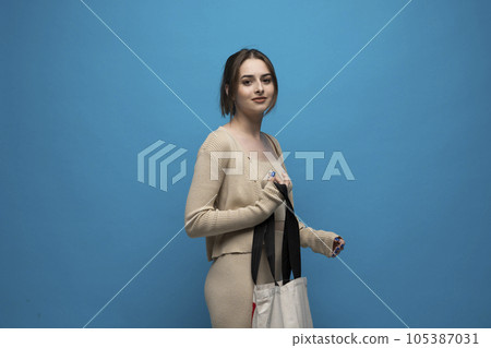 Brunette young girl holding linen shopping bag, mock up. Lady holding flax shopper handbag. Fashion and ecology concept. 105387031