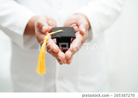 Asian woman doctor holding graduation hat in hospital, Medical education concept. 105387270