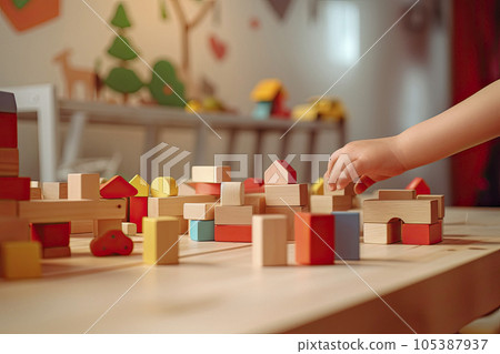 close up of a child's hand picking up a wooden toy blocks with a Children's room background 105387937
