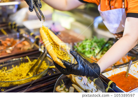 Vietnamese woman serving traditional vietnamese sandwich banh mi in street food at night Vietnamese woman serving traditional vietnamese sandwich banh mi in street food at night 105389597