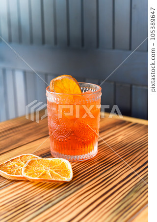 Alcohol cocktail Aperol Spritz with slise of orange on wooden table against dark wall with copy space 105389647