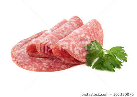 Sliced smoked sausage and parsley leaves on a white background. Sliced smoked sausage and parsley leaves on a white background. 105390076