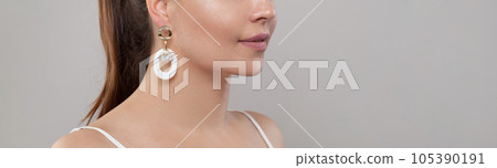 Golden earring on ear of beautiful model on grey banner background Golden earring on ear of beautiful model on grey banner background 105390191