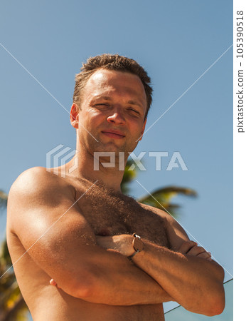 Young smiling adult man without clothes stands on the beach Young smiling adult man without clothes stands on the beach 105390518