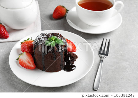 Delicious warm chocolate lava cake with mint and strawberries on table Delicious warm chocolate lava cake with mint and strawberries on table 105391242