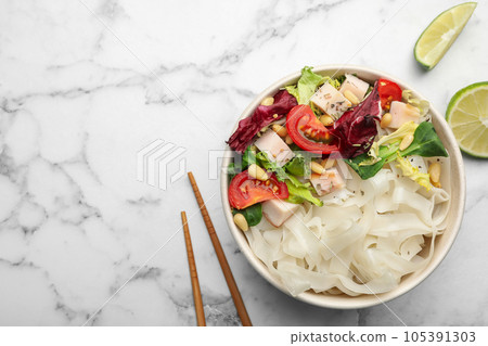 Tasty cooked rice noodles with chicken and vegetables on white marble table, flat lay. Space for text 105391303