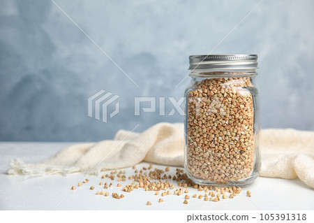 Jar with green buckwheat on white table. Space for text 105391318