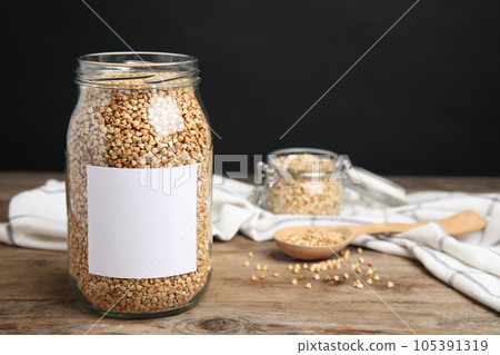 Organic green buckwheat in jar with blank label on wooden table 105391319